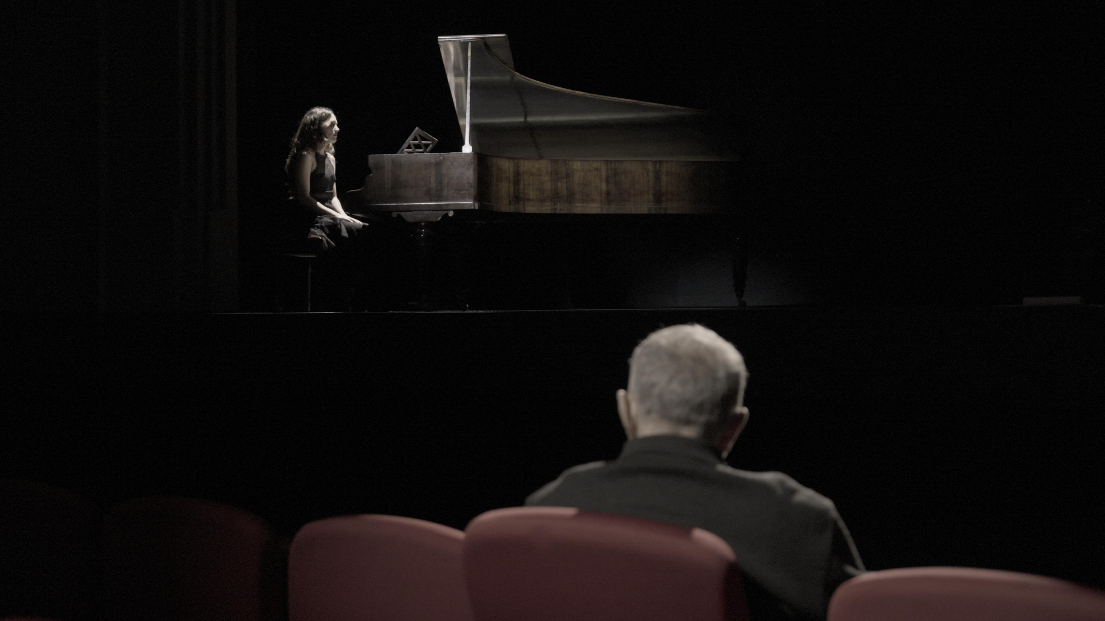 Escena del projecte audiovisual Primera Mirada en un espai escènic municipal, amb piano i públic, treballant la relació entre intèrpret, espai i mirada.